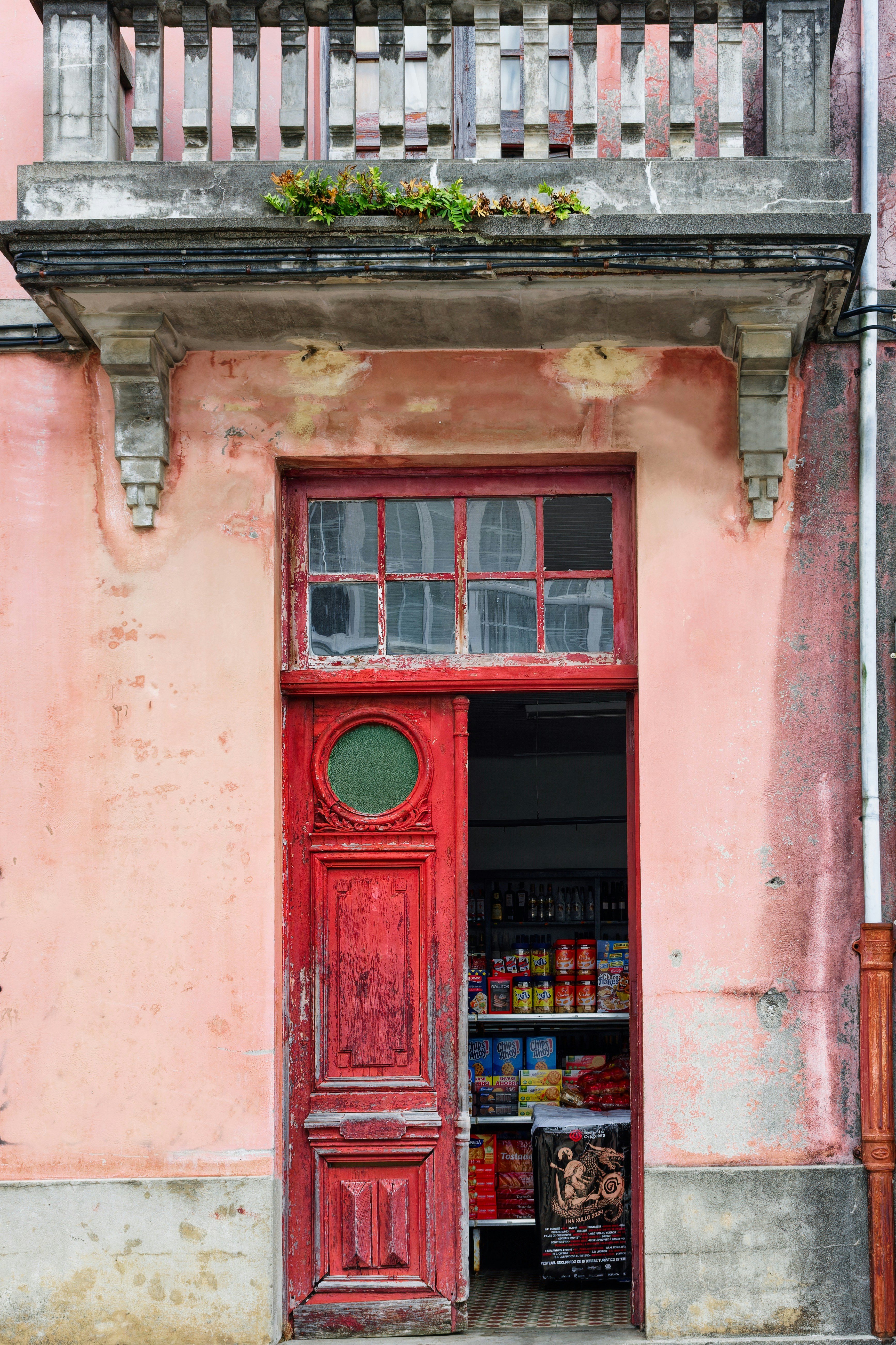 A red door is open in front of a pink building