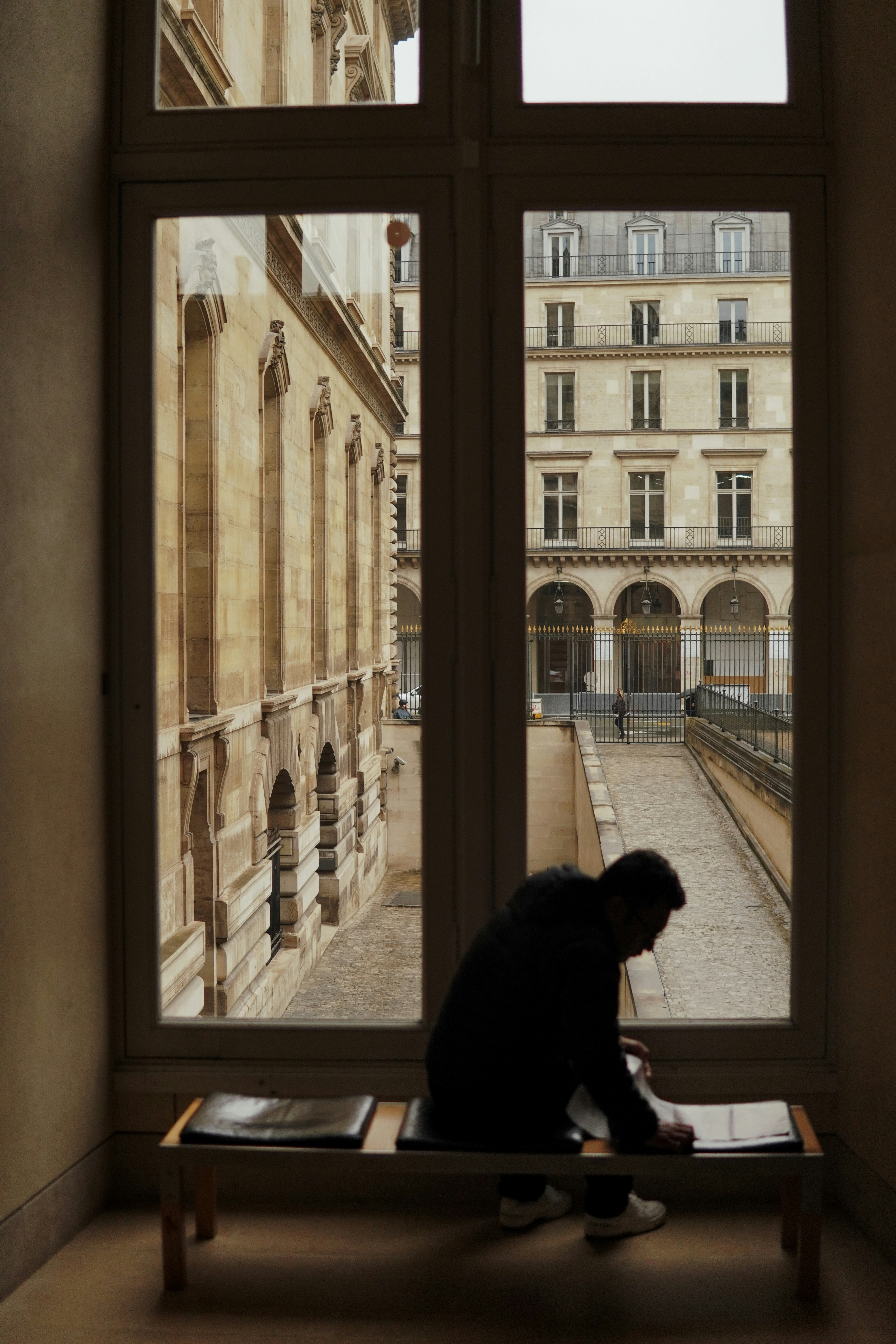 A person sitting on a bench in front of a window
