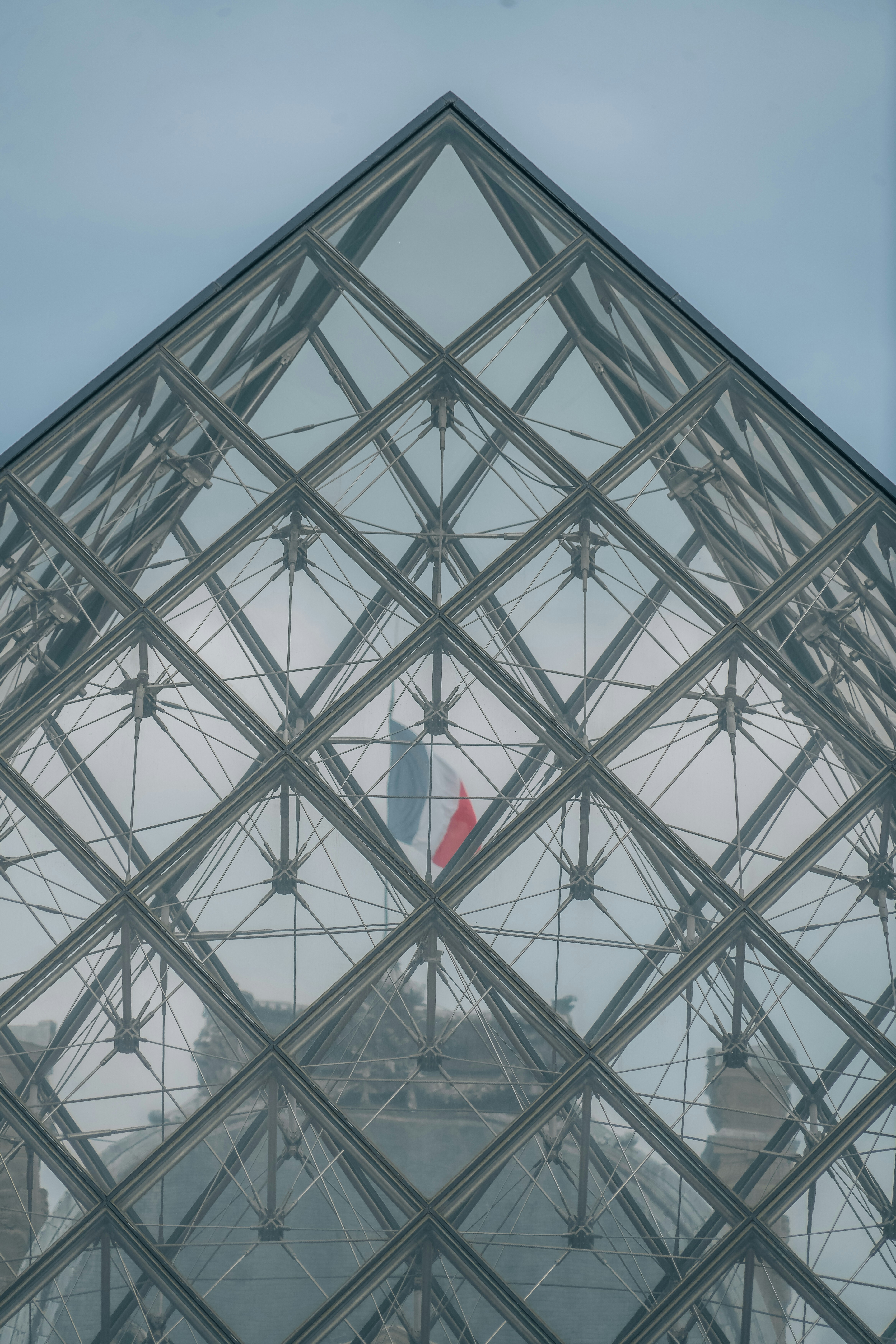 A large glass pyramid with a flag on top of it