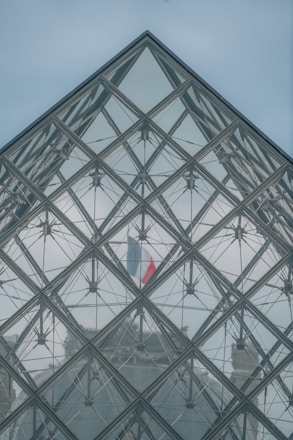 A large glass pyramid with a flag on top of it