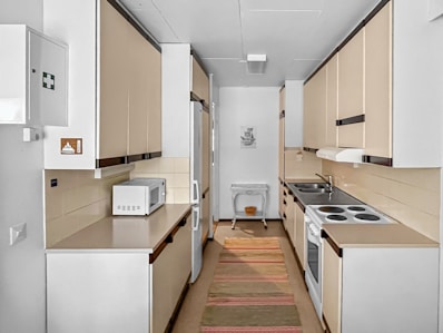 A narrow galley kitchen with a sink and microwave