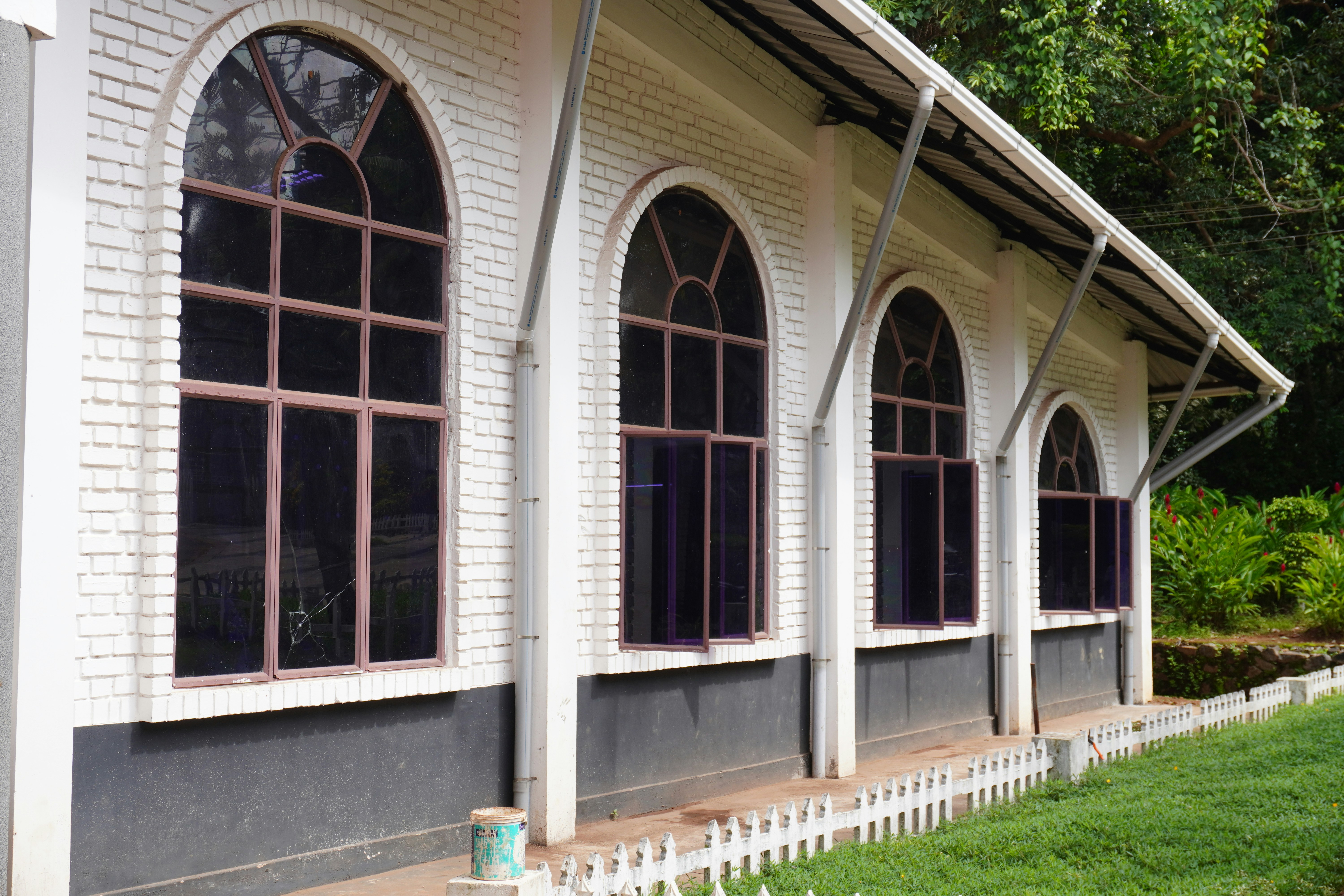 A white building with arched windows and a white picket fence