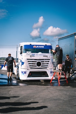 A group of men standing next to a white truck
