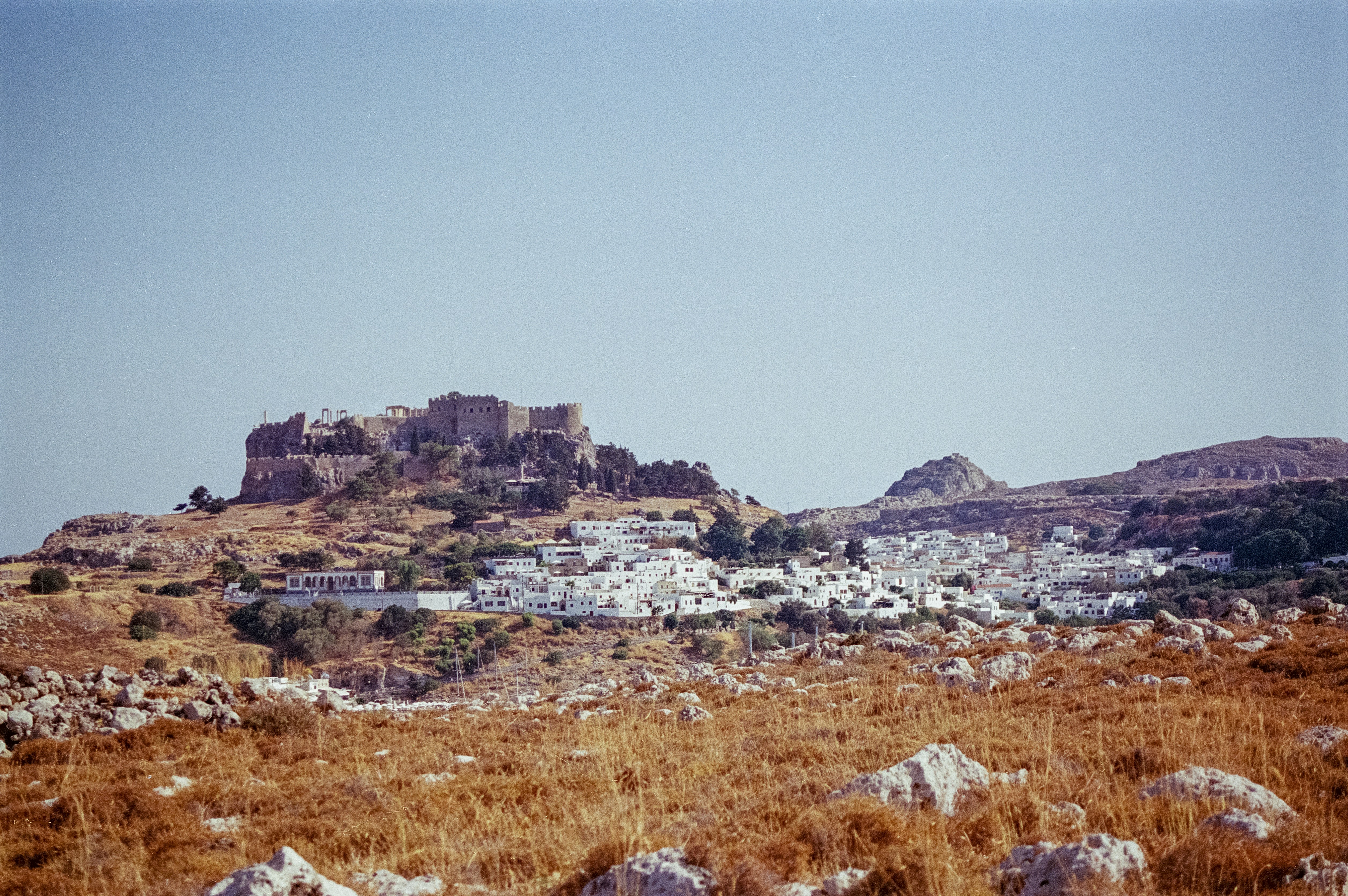 A field with rocks and grass and a hill in the background