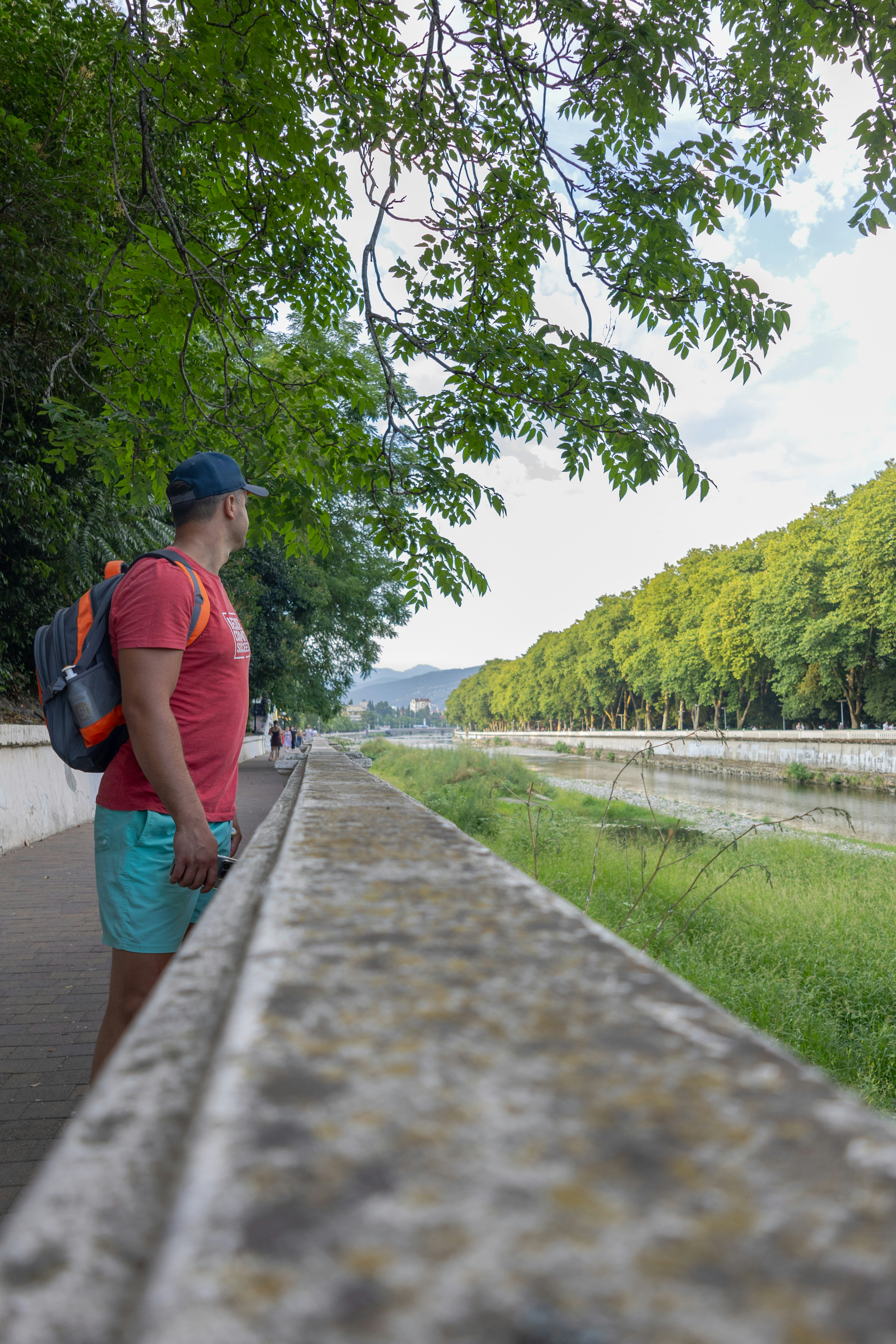 A man walking down a sidewalk next to a river