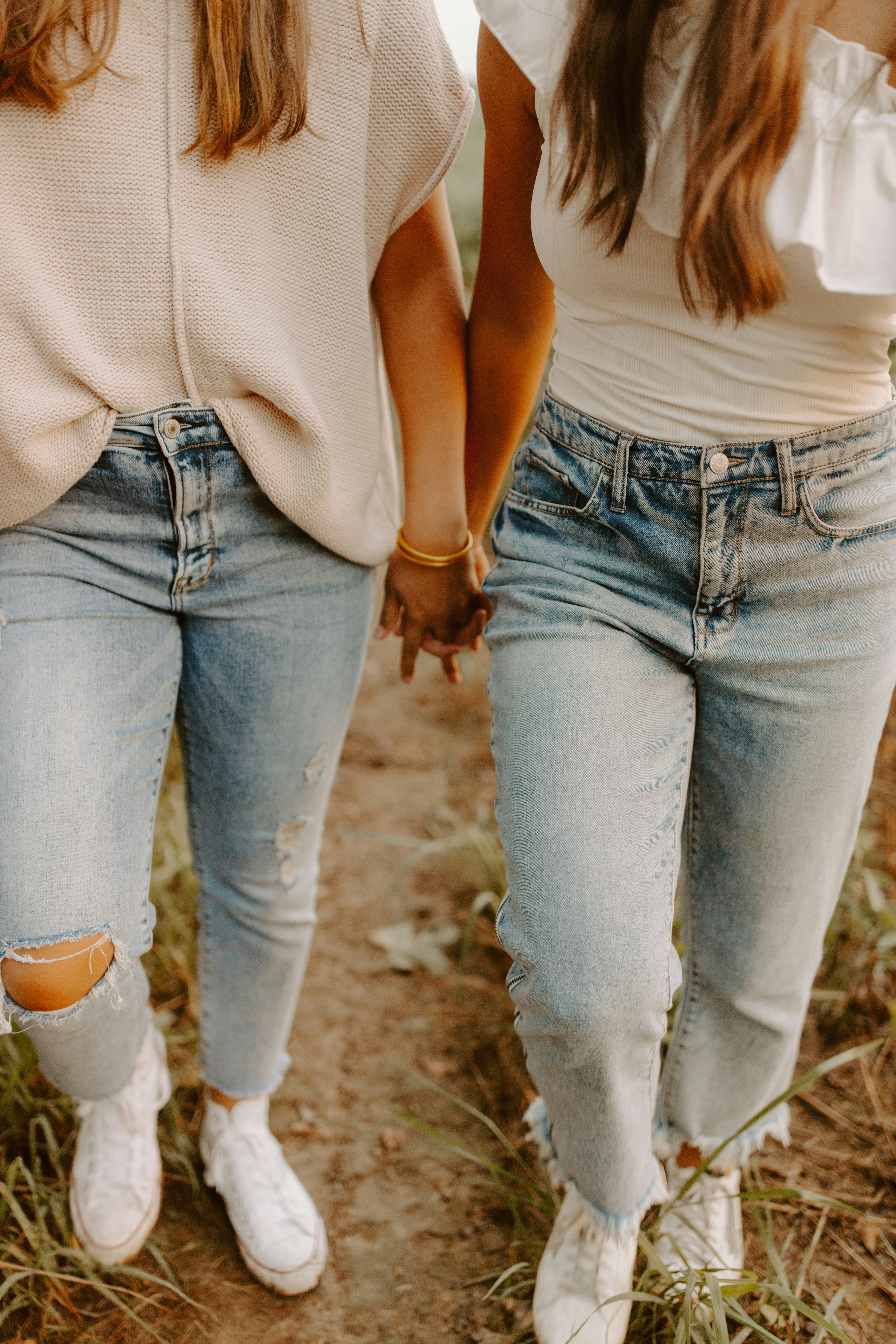 Two girls walking down a dirt road holding hands