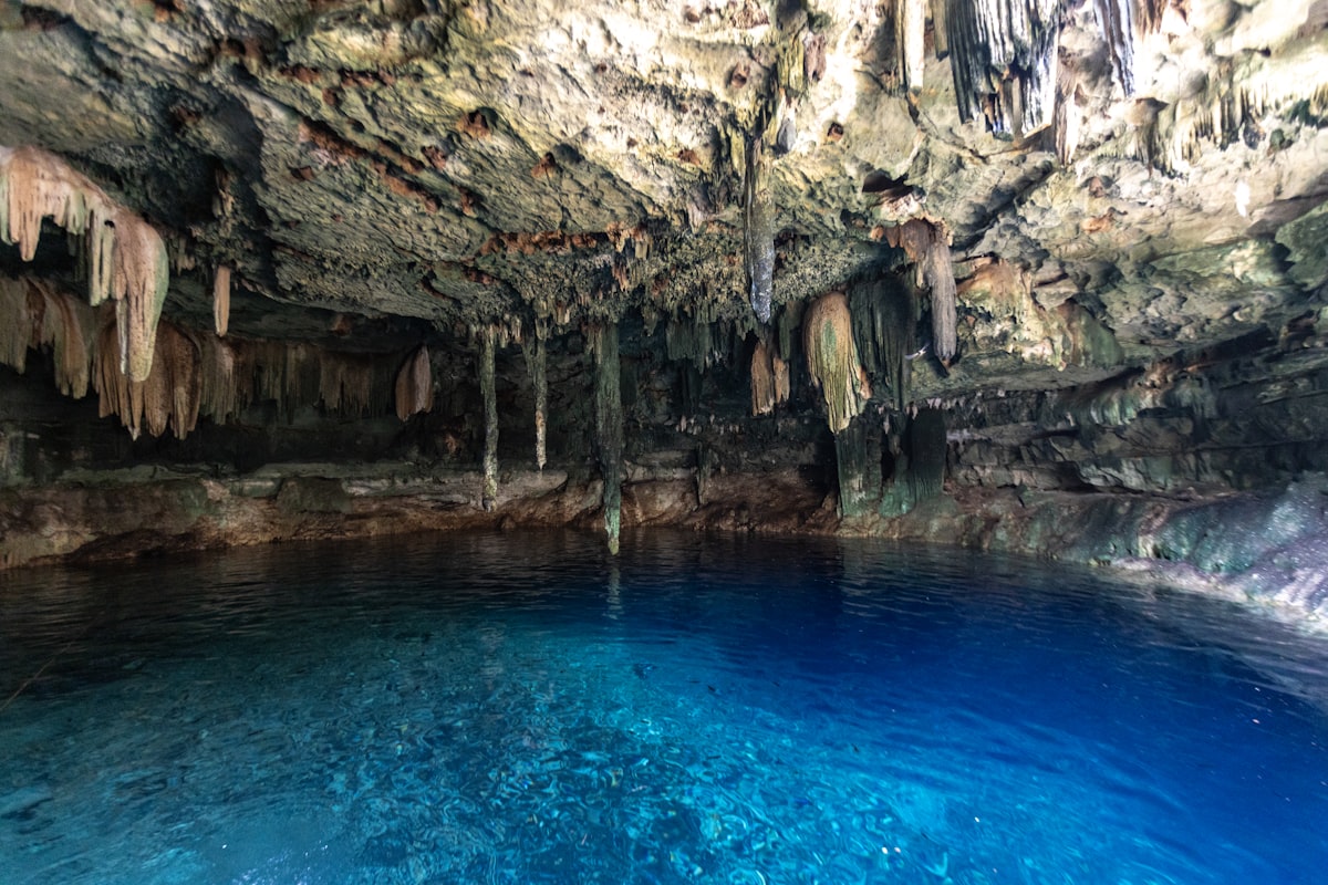 Stunning blue cenote cave with crystal clear water and dramatic limestone formations in the Yucatan