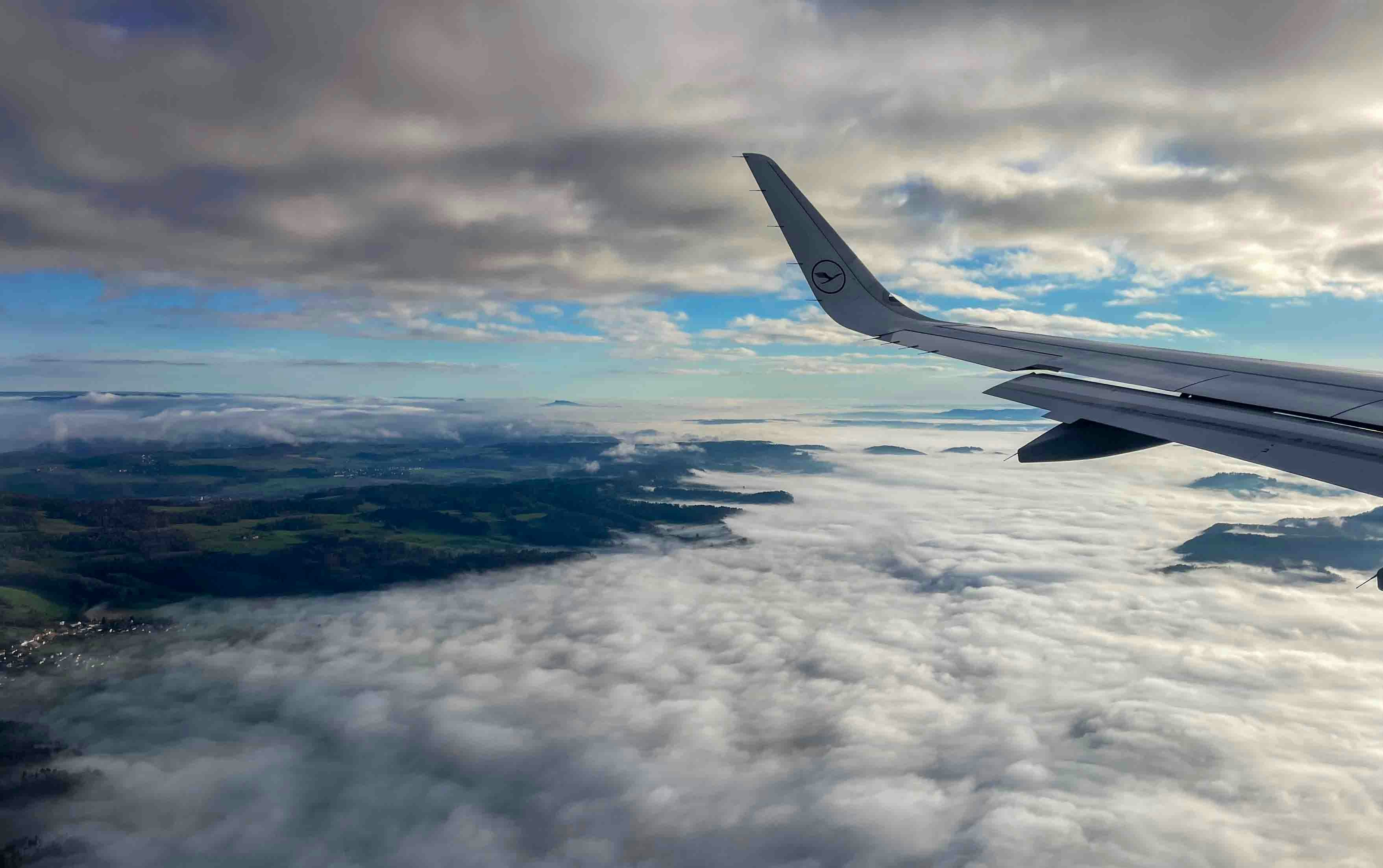 A view of the wing of an airplane in the sky, Aerial view from an airplane flying above a layer of clouds. The aircraft