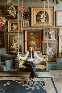 A woman sitting on a swing in a room filled with paintings