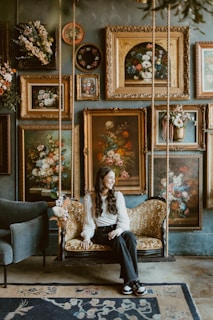 A woman sitting on a swing in a room filled with paintings