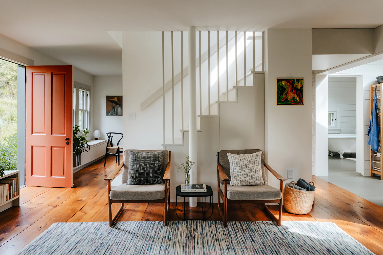 A living room with an open floor plan, a staircase, and a red front door