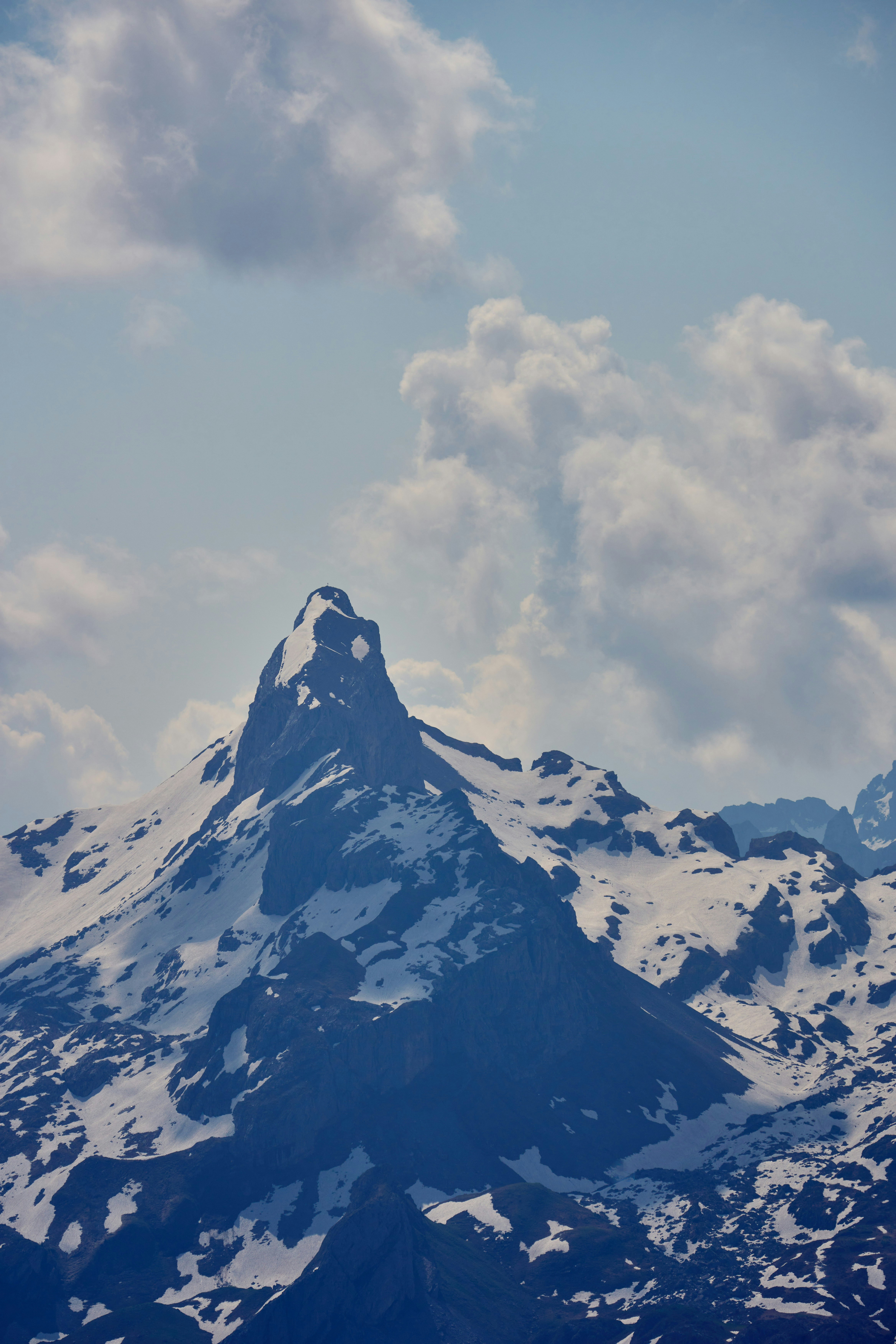 A snow covered mountain under a cloudy blue sky photo – Free ...