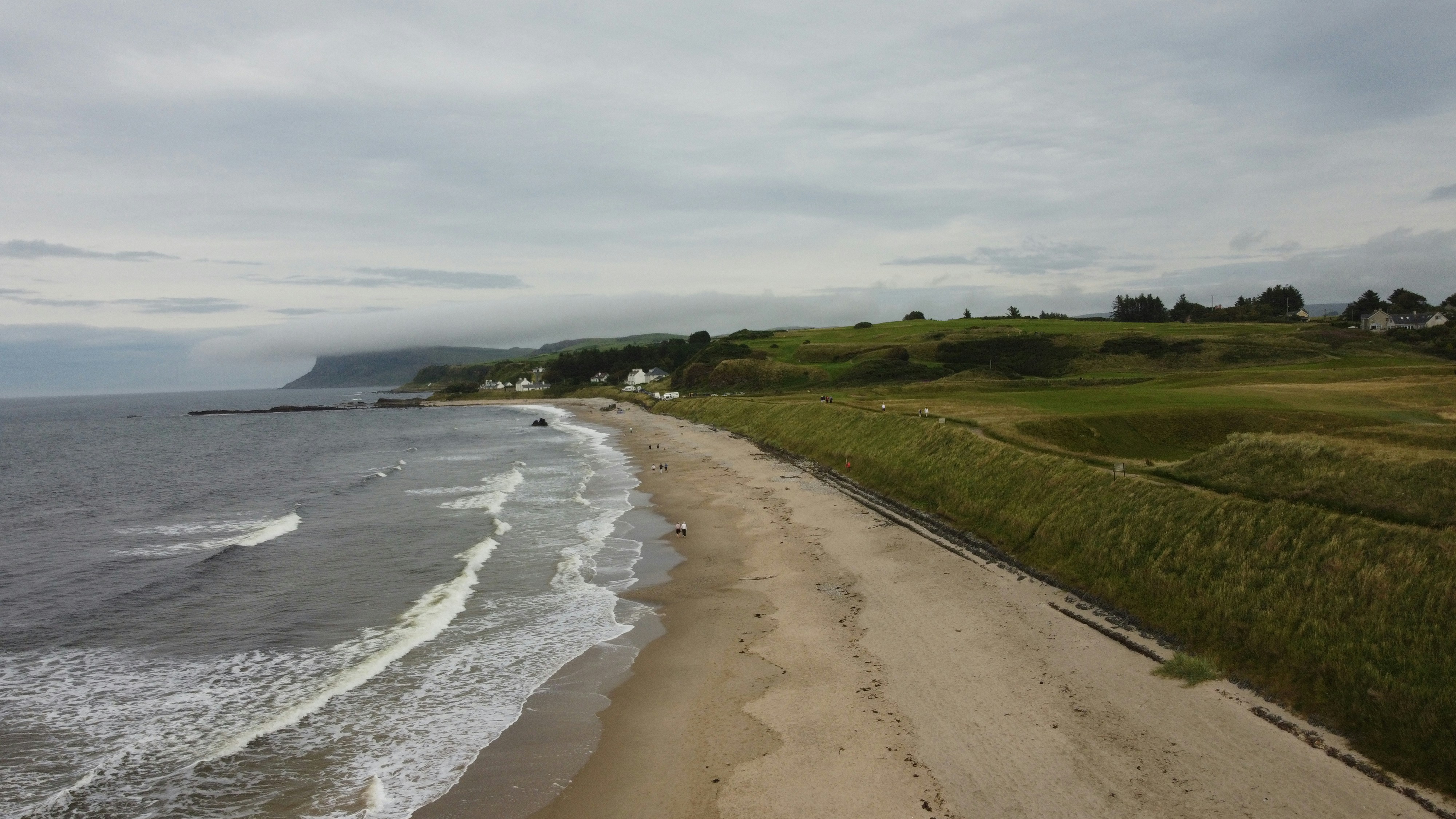 A sandy beach next to the ocean under a cloudy sky