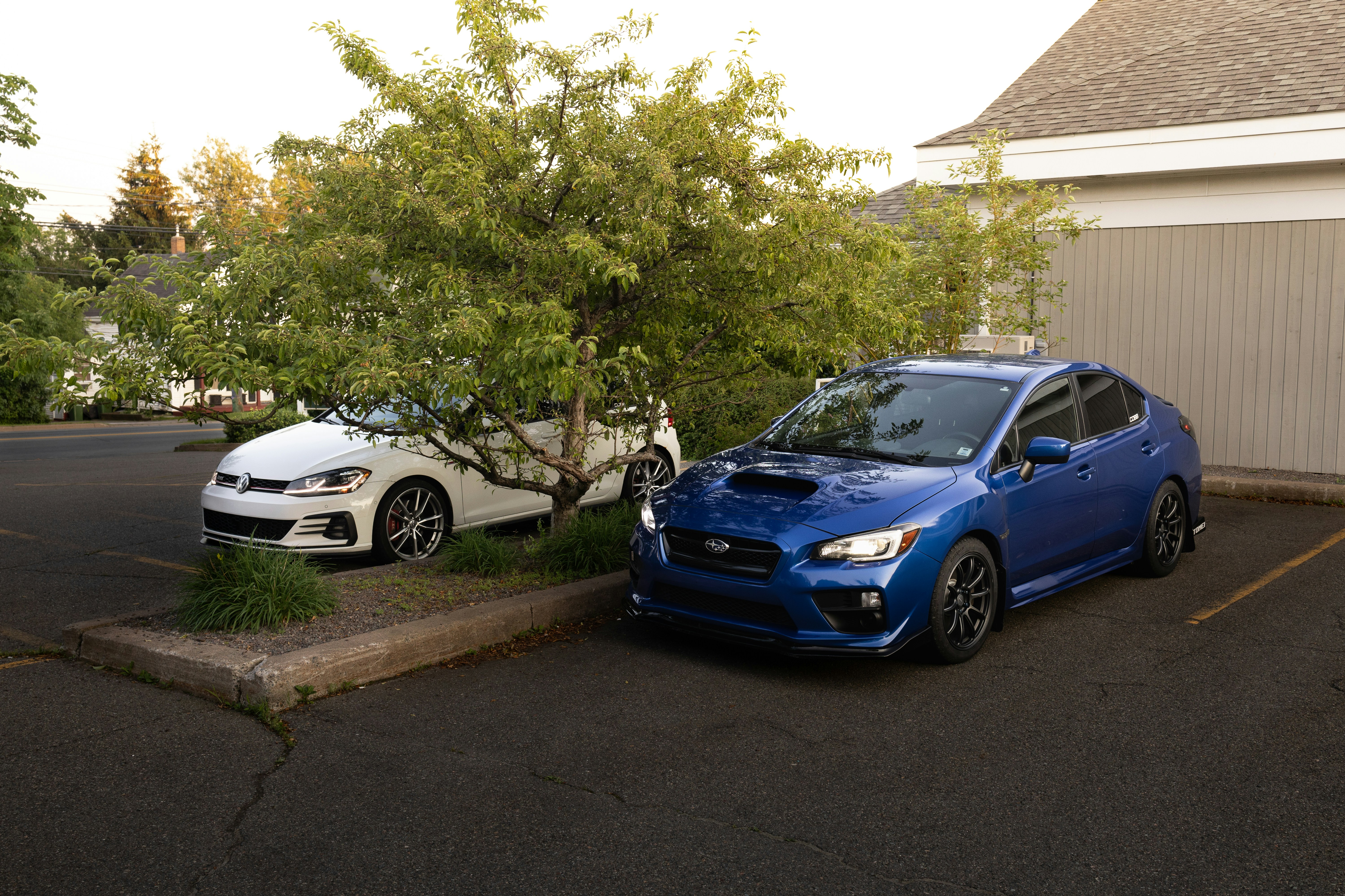 Family standing by an electric car charging in a suburban driveway