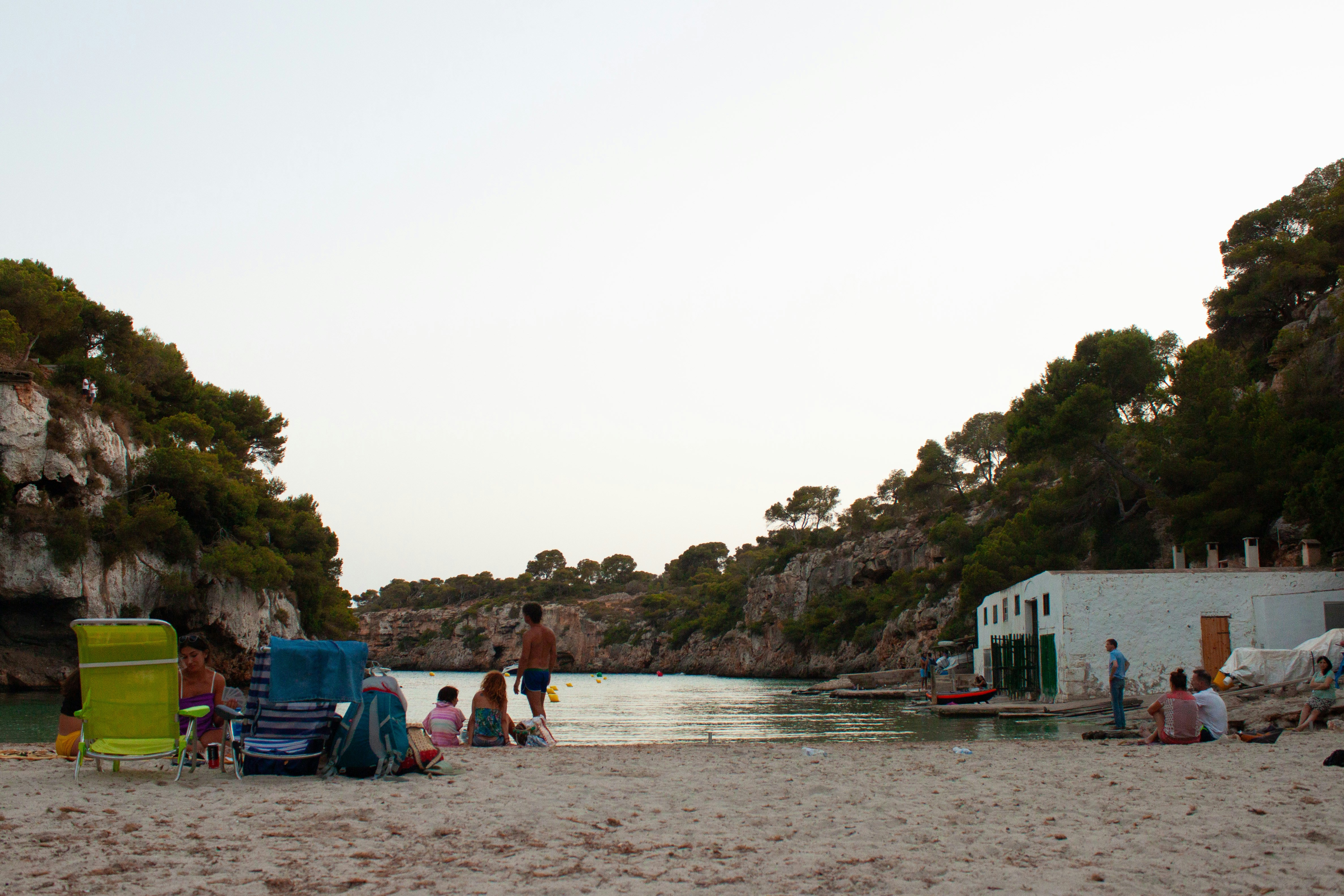 A group of people sitting on a beach next to a body of water