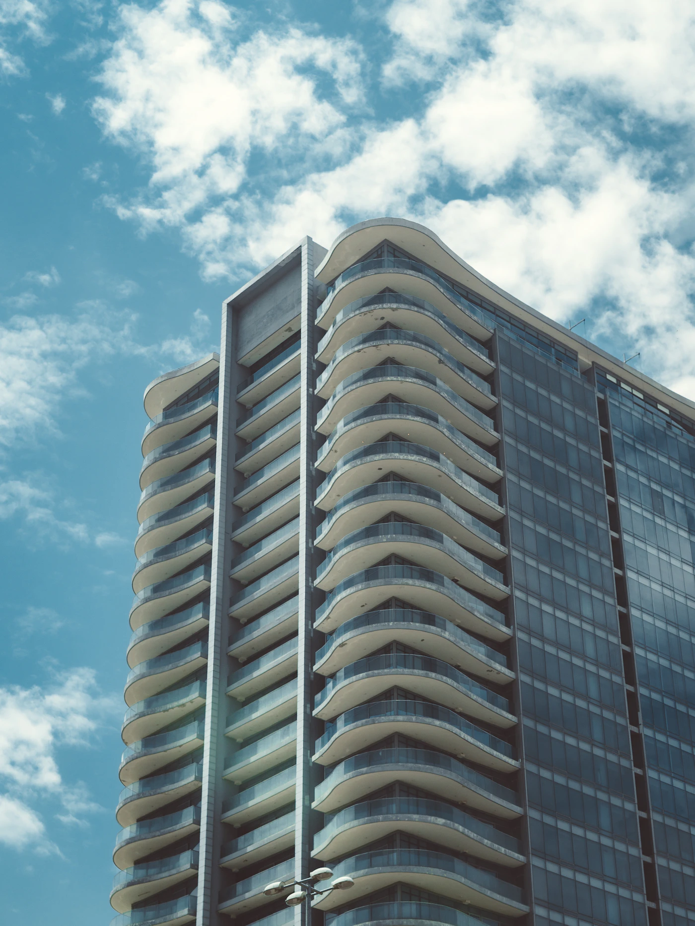 Curved glass office tower against a blue sky
