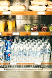 A store shelf filled with bottled water and fruit