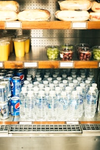 A store shelf filled with bottled water and fruit