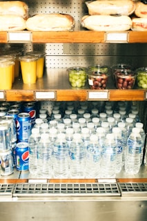 A store shelf filled with bottled water and fruit