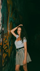 A woman standing in front of a graffiti covered wall
