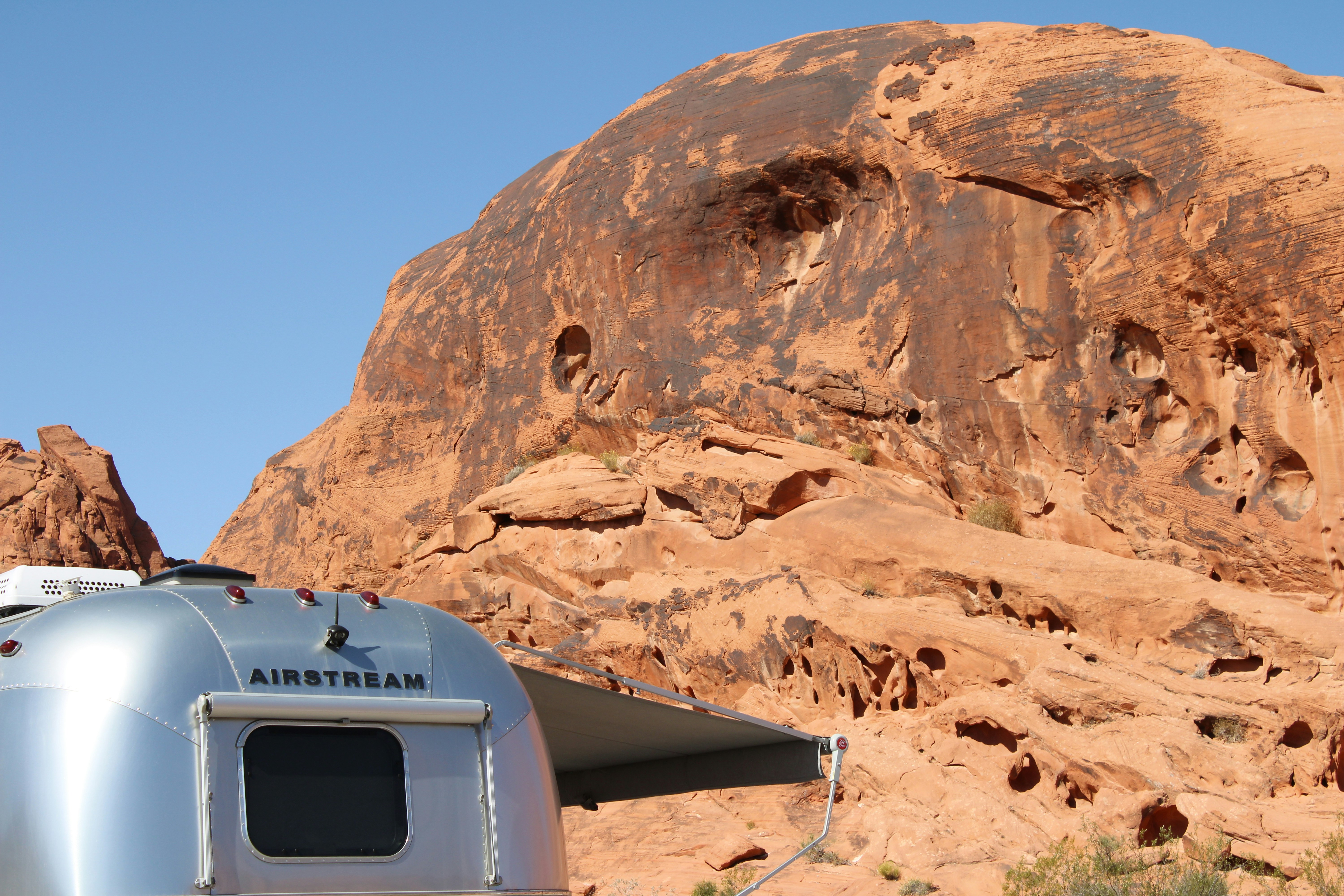A silver trailer parked in front of a mountain, 