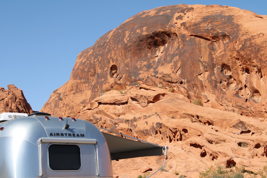 A silver trailer parked in front of a mountain,