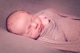 A baby wrapped in a blanket is smiling