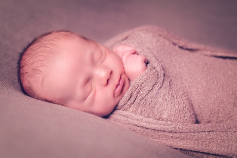 A baby wrapped in a blanket is smiling