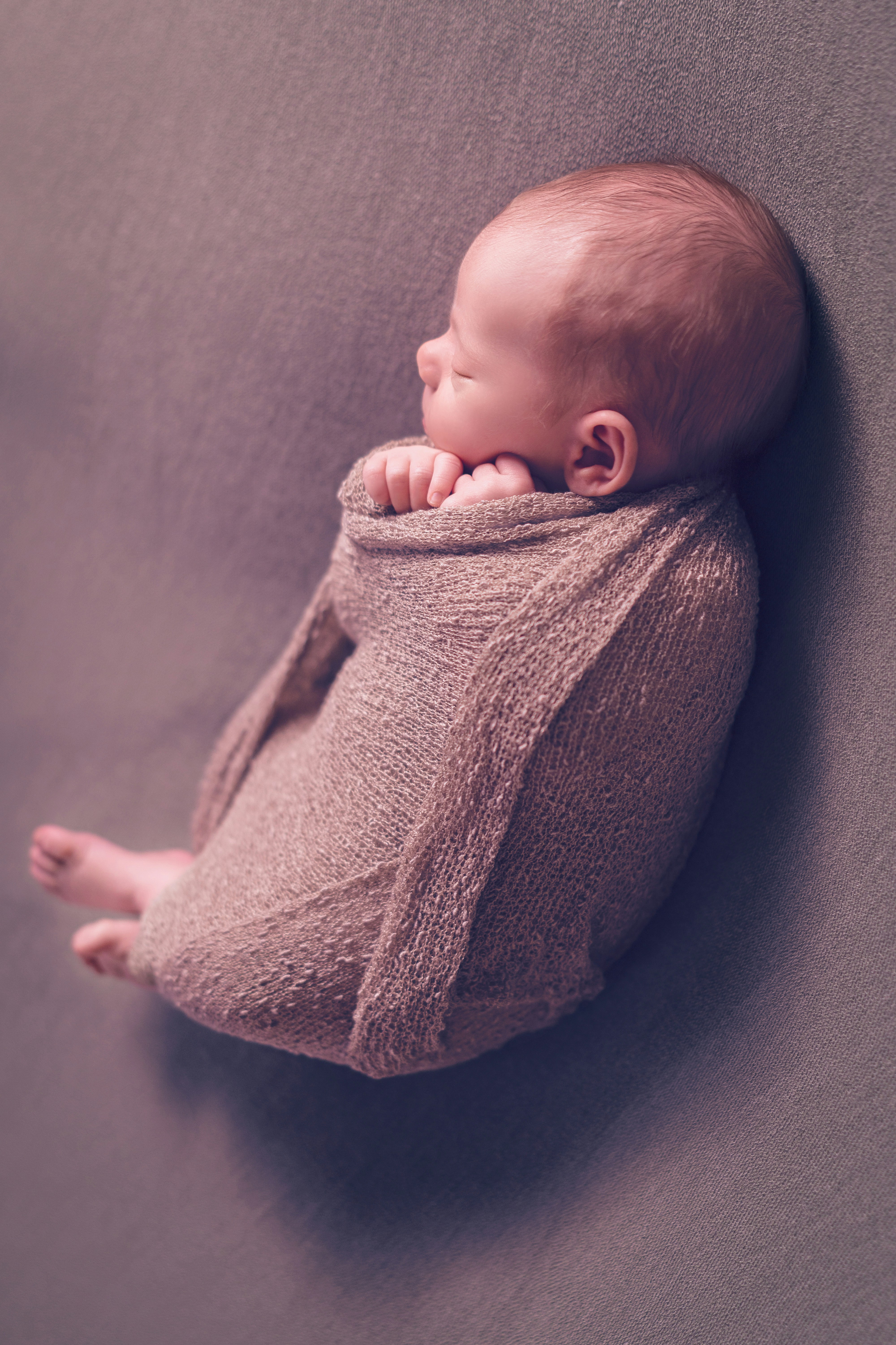 A baby wrapped in a blanket is laying down