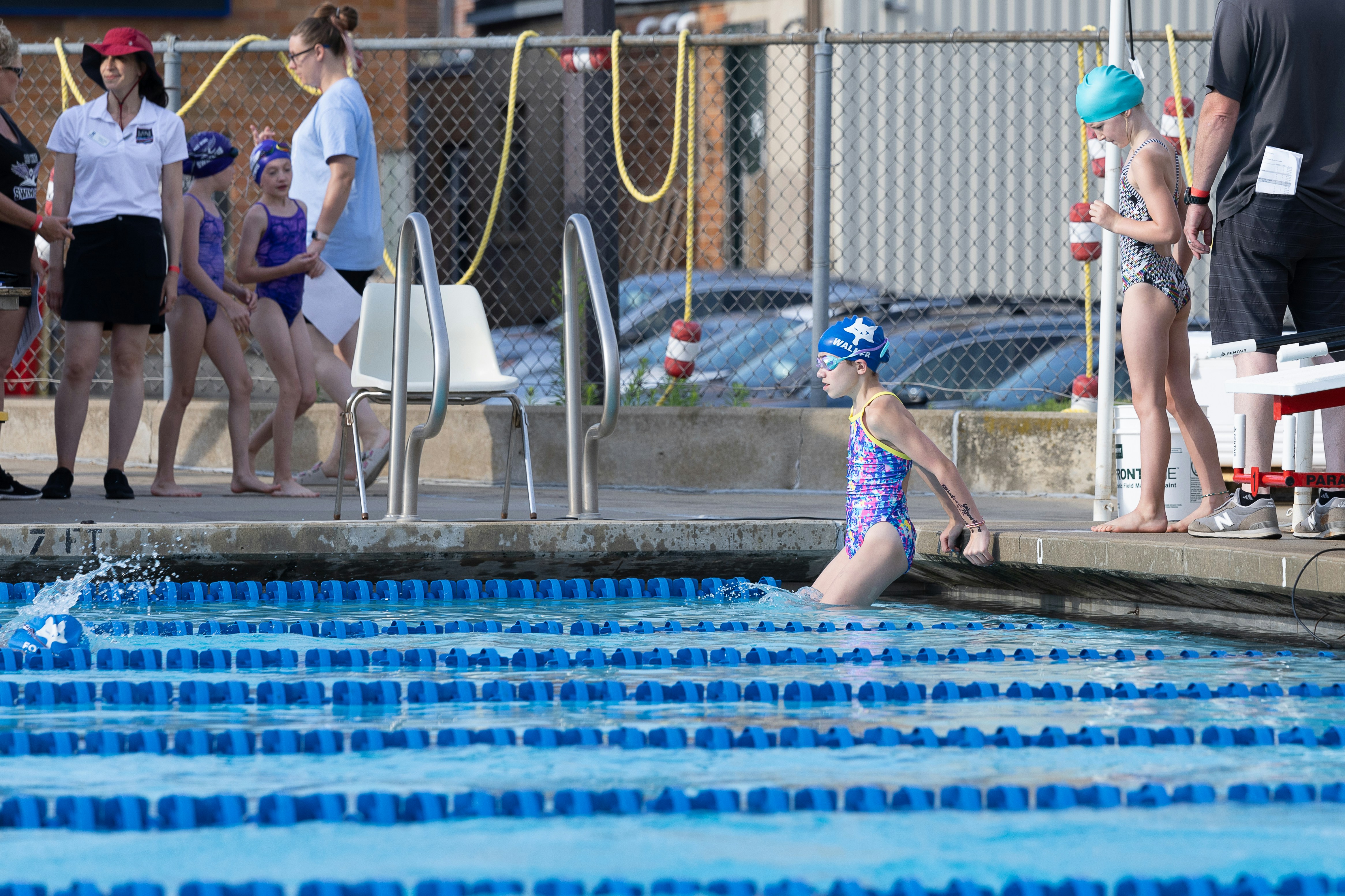 A little girl in a swim suit jumping into a pool