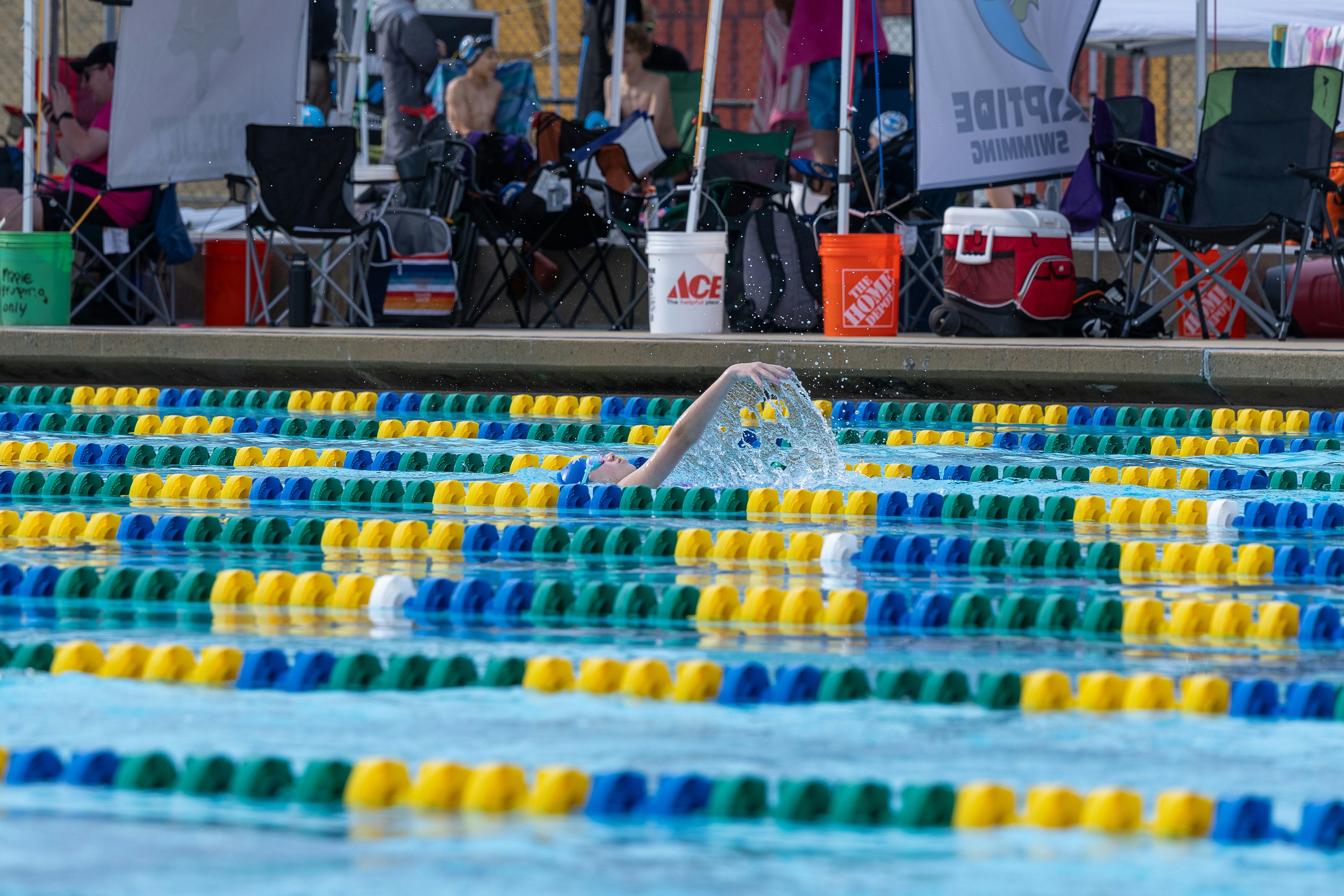 A man swimming in a pool surrounded by people
