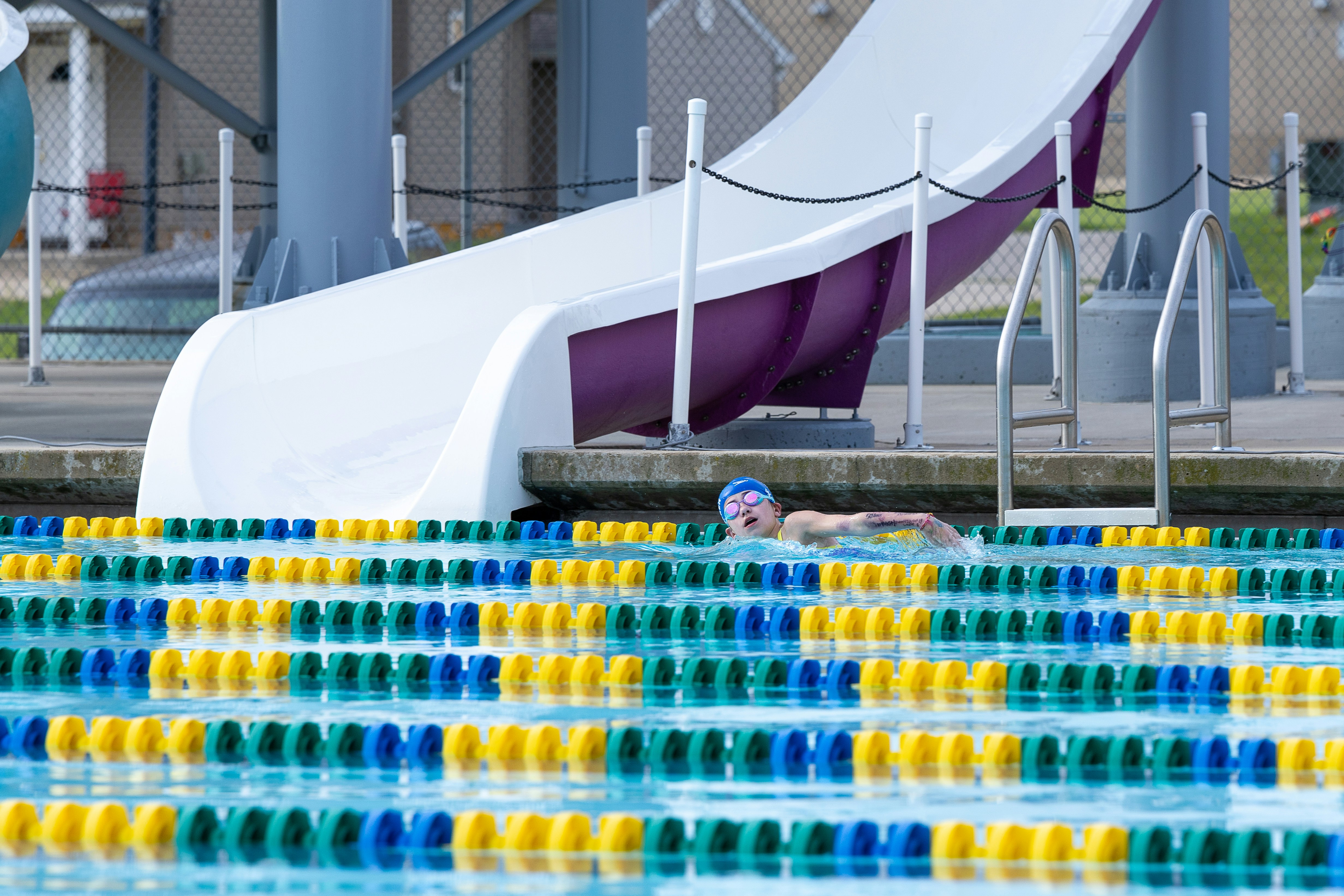 A man swimming in a pool next to a water slide