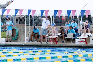 A group of people standing around a swimming pool