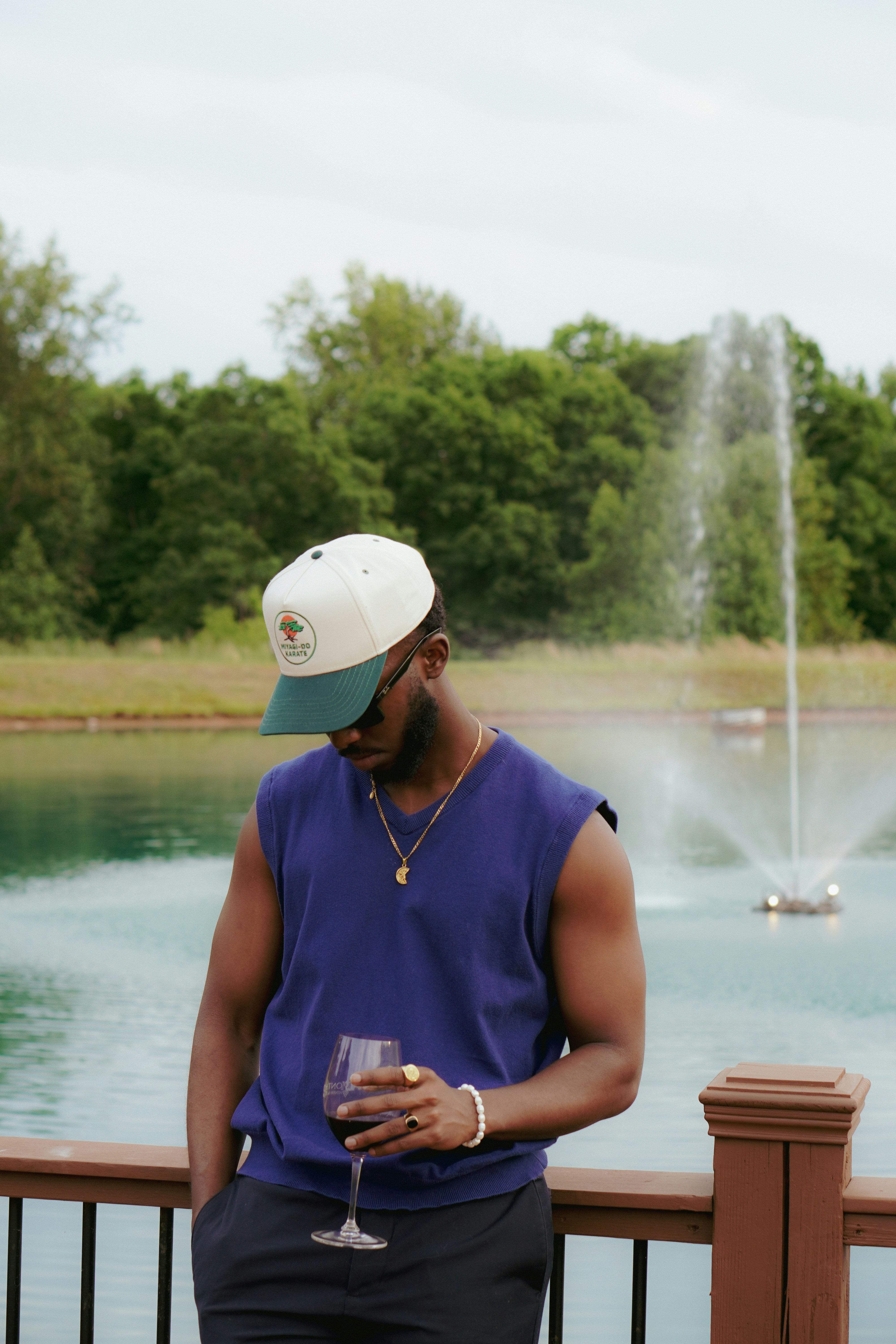 A man standing next to a lake holding a wine glass