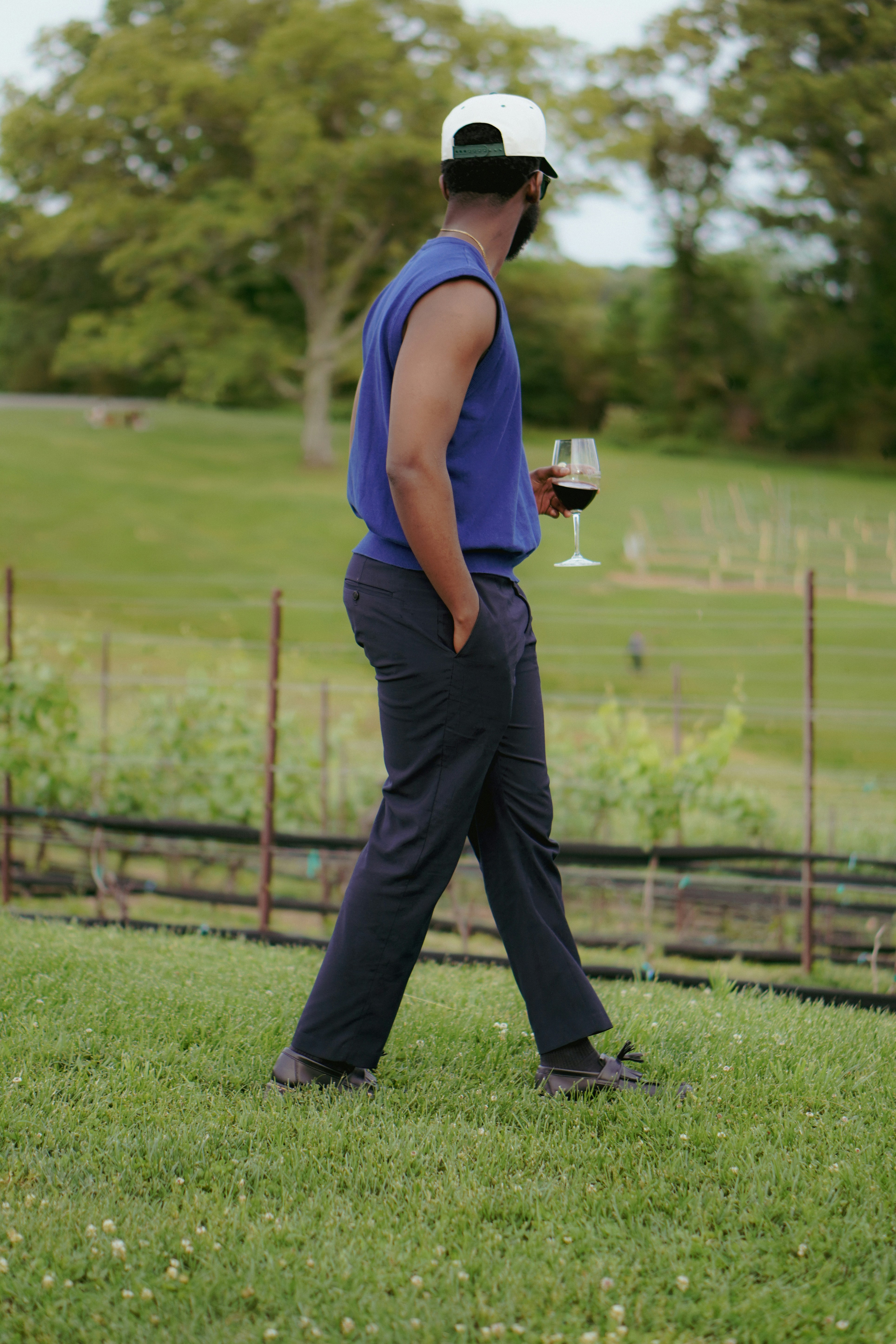 A man walking in the grass with a glass of wine