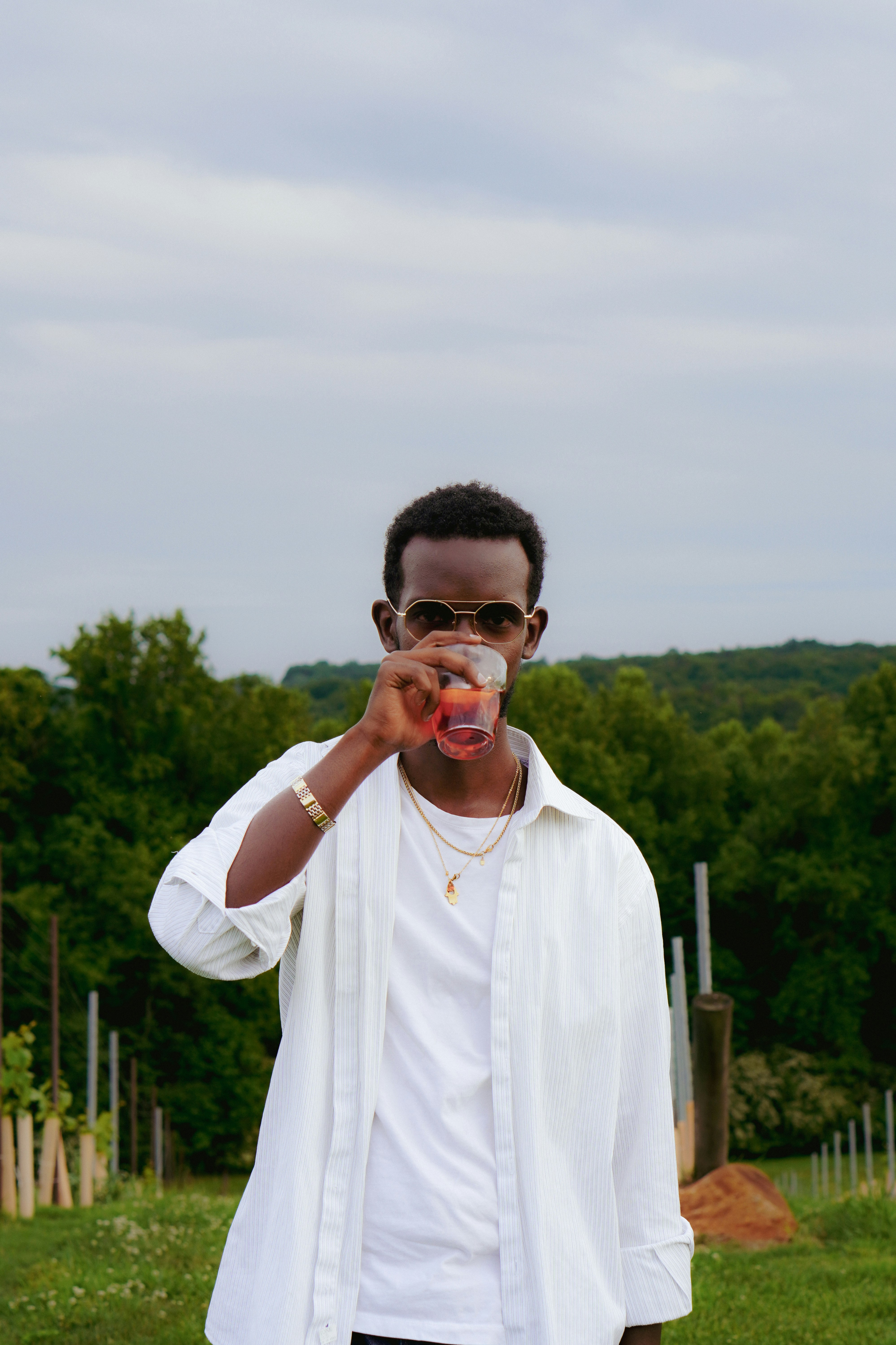 A man standing in a field drinking a drink