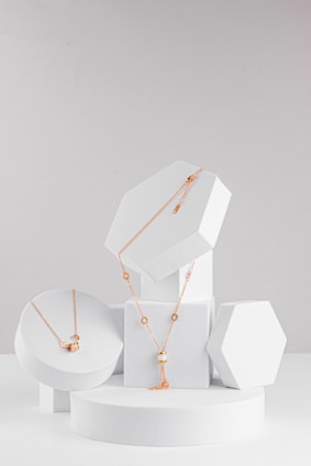 A set of three white boxes with gold necklaces