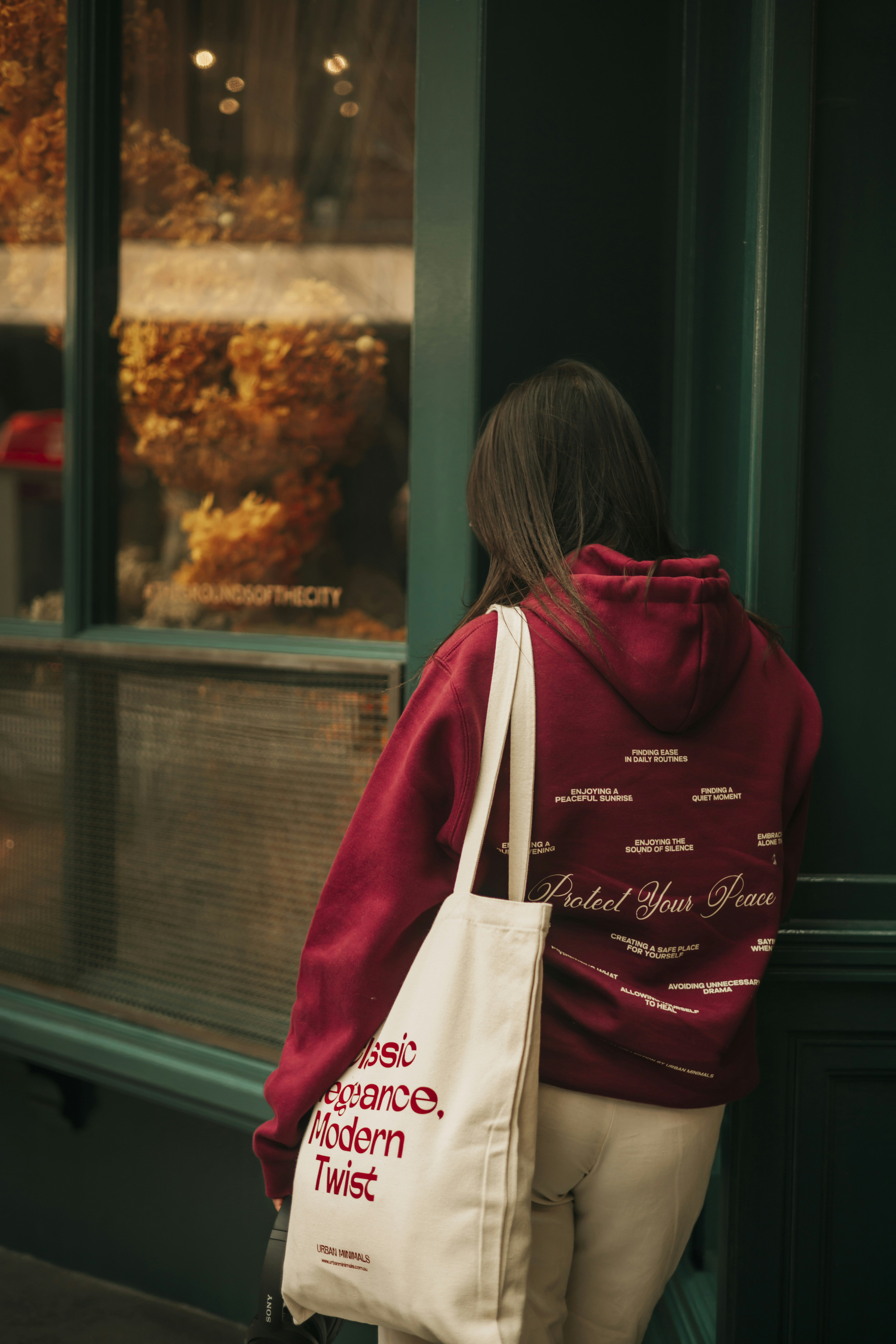 A woman standing outside of a store with a tote bag