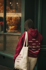 A woman standing outside of a store with a tote bag