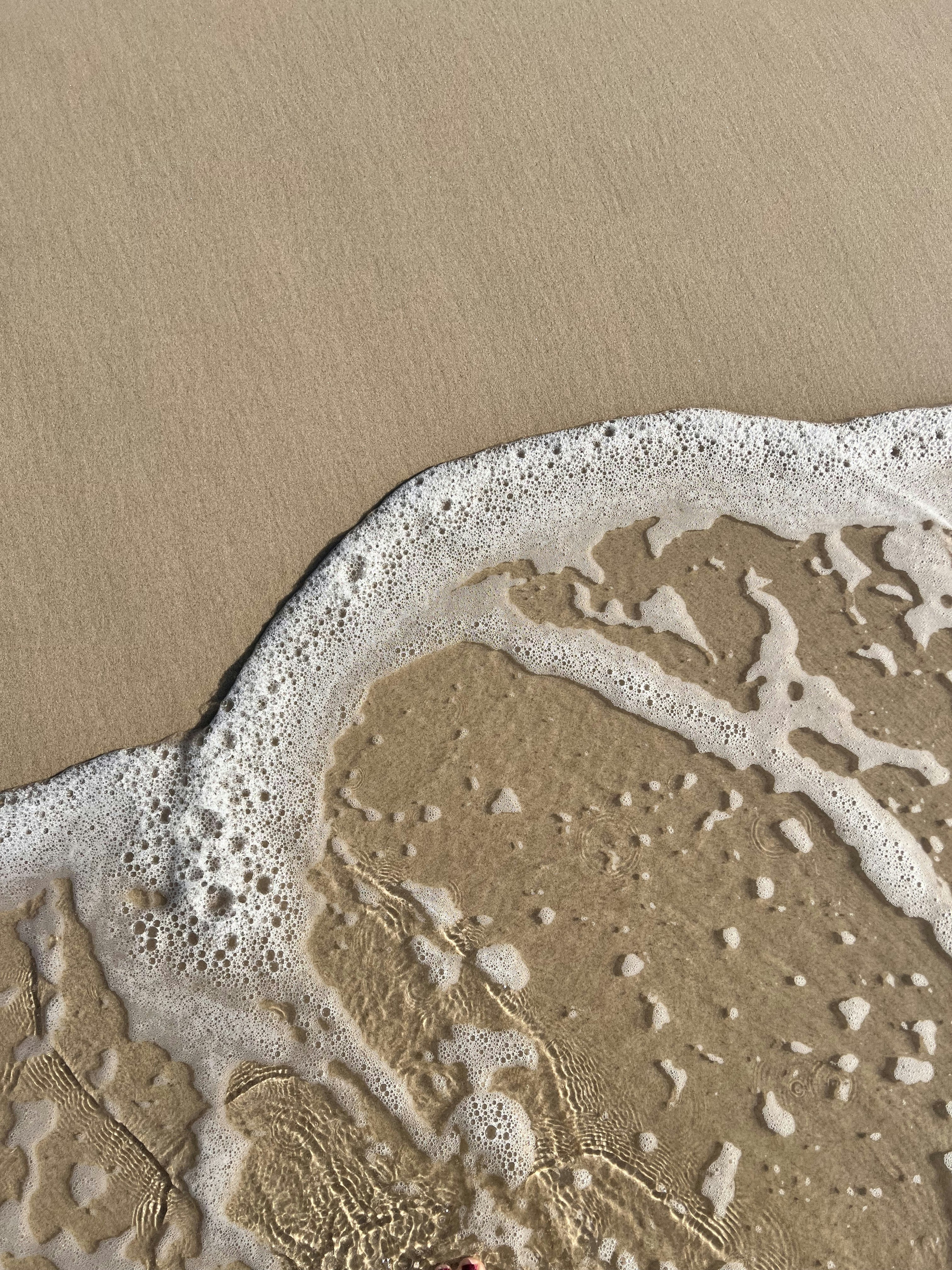 A sandy beach with a wave coming in to shore