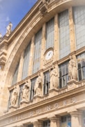 A large building with a clock on the side of it Gare du Nord