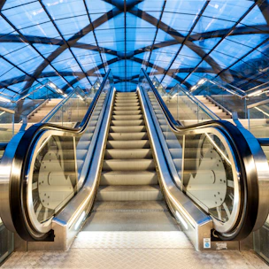 An escalator in a train station with a skylight