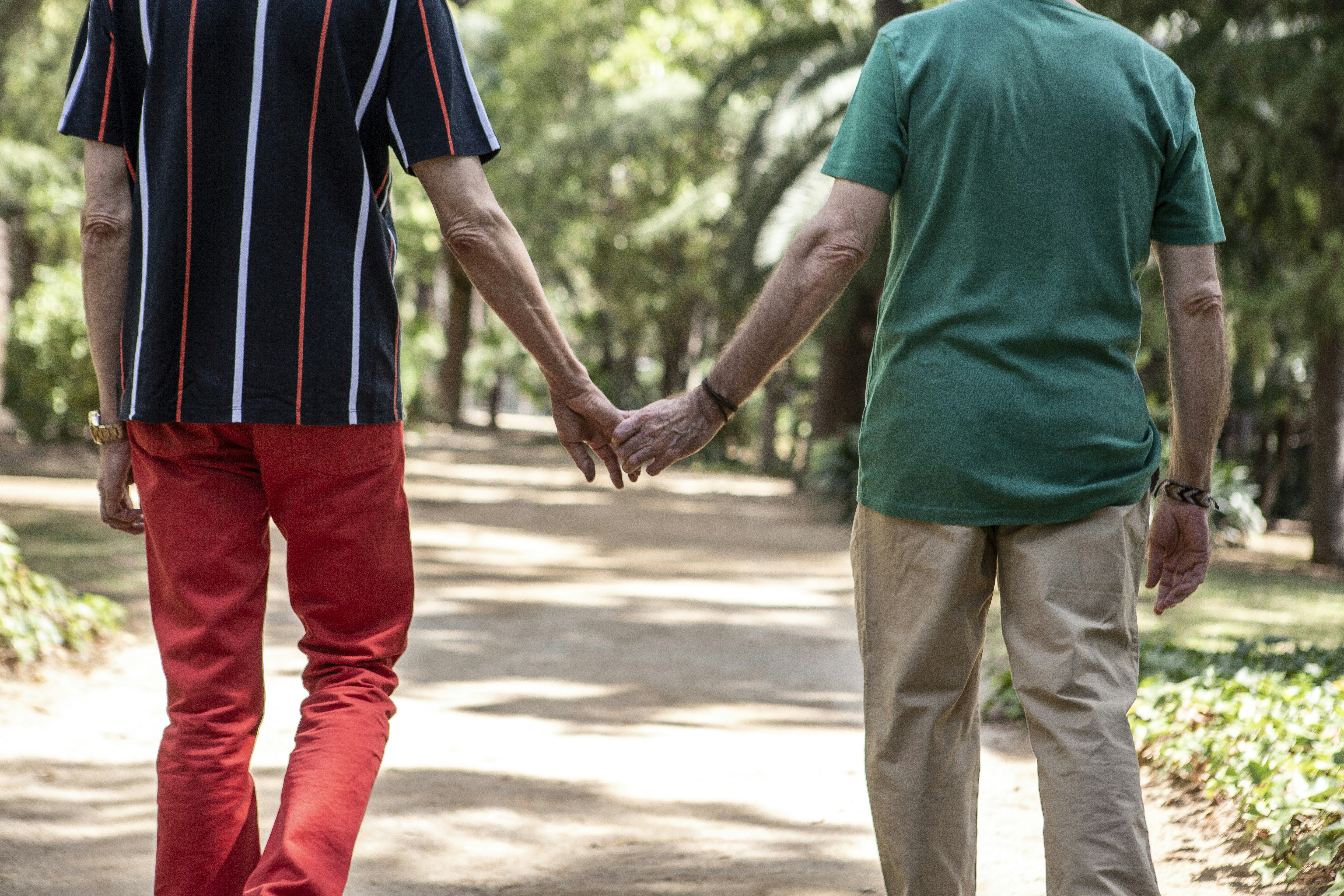 A man and a woman holding hands walking down a path