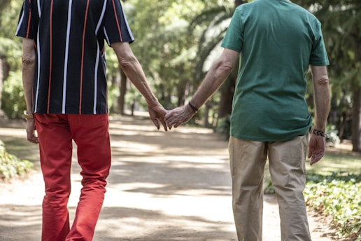 A man and a woman holding hands walking down a path