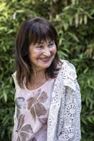 A woman standing in front of a bush smiling