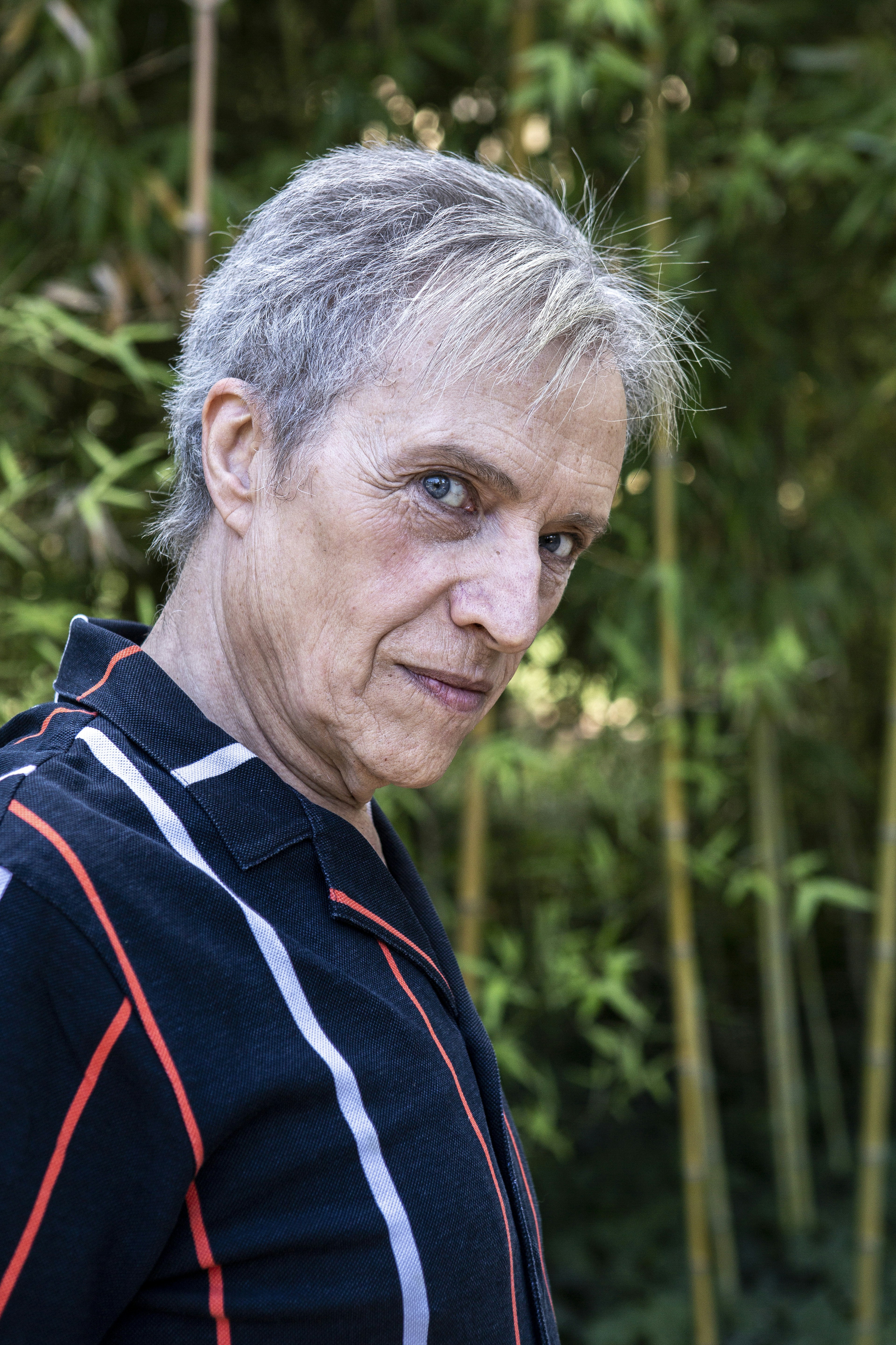 A man with grey hair standing in front of bamboo trees