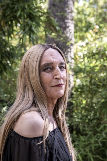 A woman with long hair standing in front of trees
