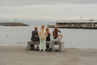 A group of people sitting on a bench next to a body of water