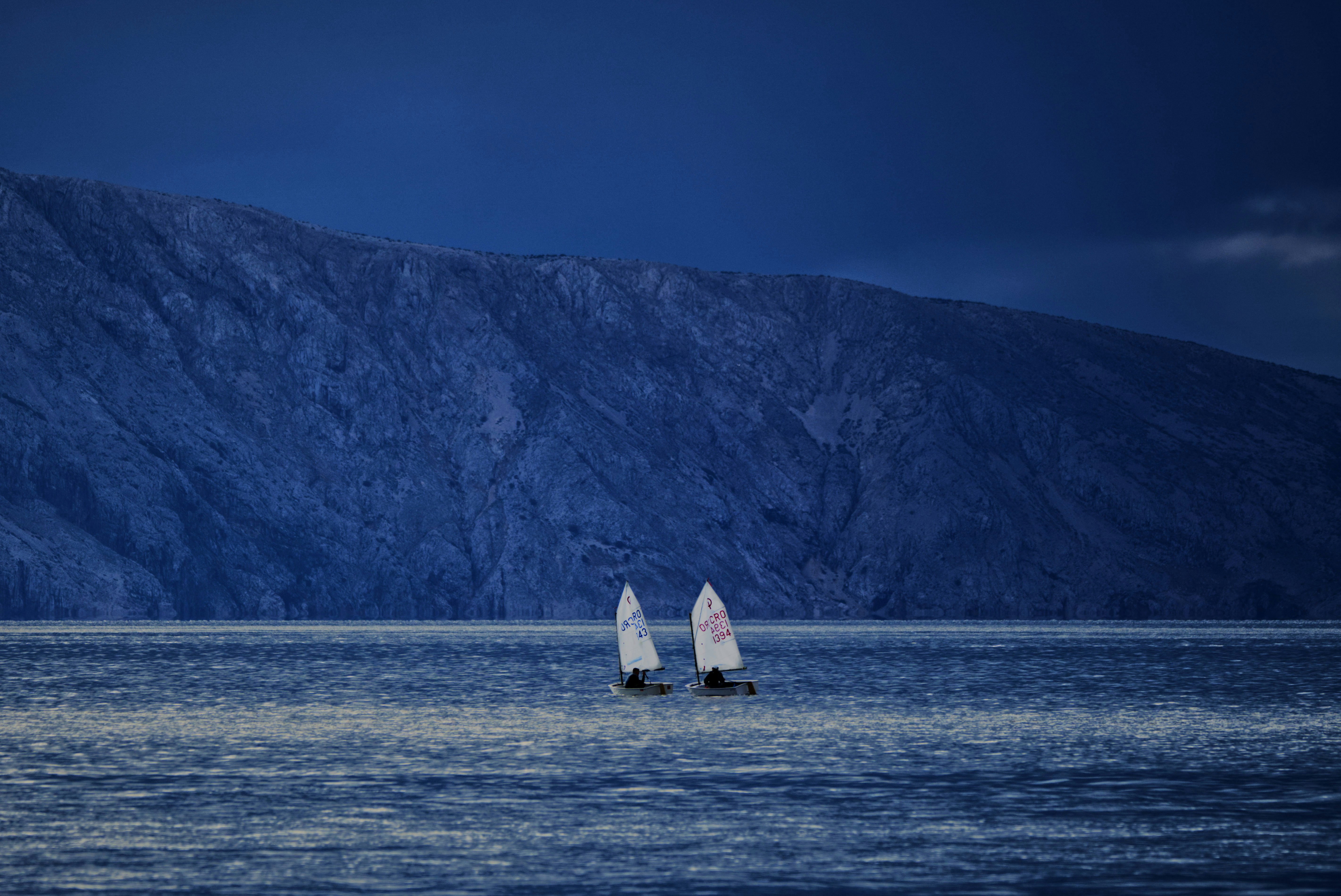 Deux voiliers dans l’eau avec une montagne en arrière-plan