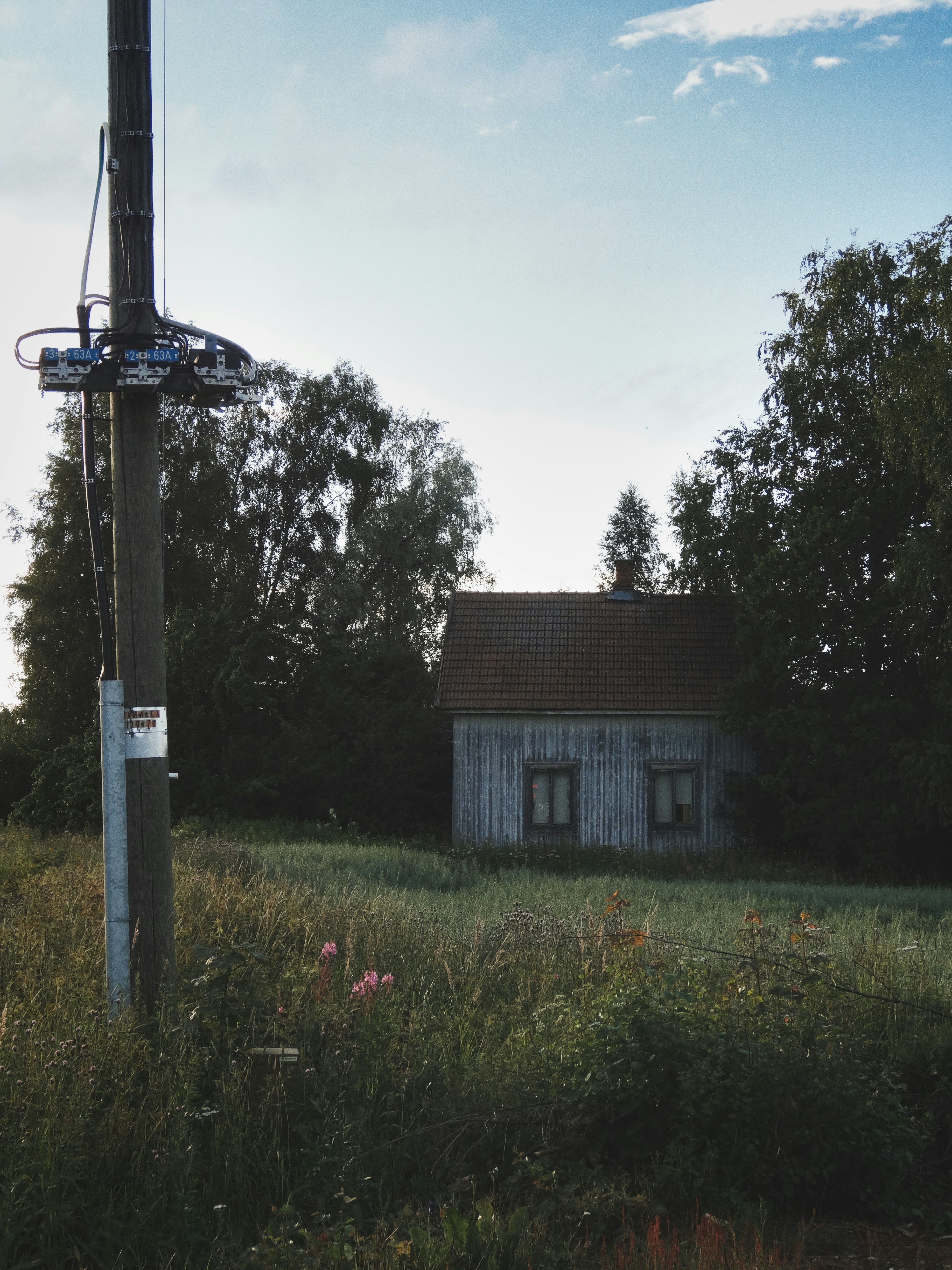 A house in the middle of a field with a satellite dish on top of it